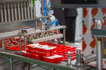 Process of automatic ketchup sauce cups filling and sealing machine. Food industry