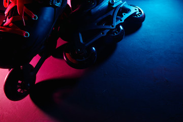 Close up view of roller skates inline skate or rollerblading on dark grunge background in neon blue...