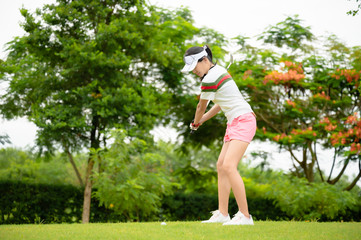 woman golf player in action being setup to hit the golf ball away from rough of fairway to the...