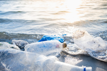 Empty plastic bottles on the beach, seashore and water pollution concept. Trash (empty beverage...