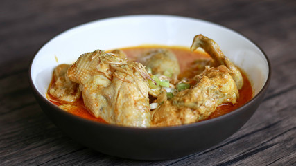 Indonesian gulai ayam or Indonesian chicken curry in a bowl on wood background.