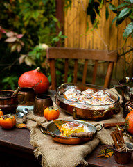 Autumn outdoor still life with pumpkin cinnamon buns in oval glass dish on wooden table