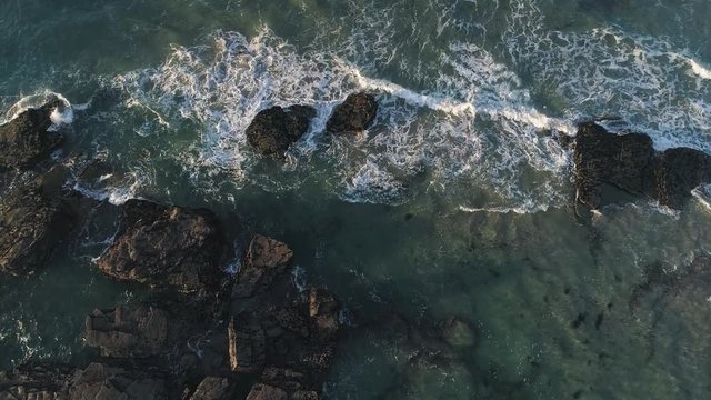 Aerial 60fps Slow motion: Playa de las Catedrales Galicia Spain at Sunset. Beach of spectacular cliffs and cracks facing Atlantic ocean. Popular touristic place