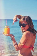 Cute woman drinking juice on the beach. Summer concept.