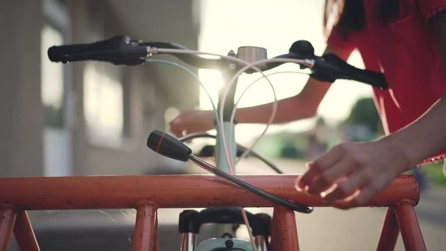 Girl fastening bicycle lock on street parking at sunset