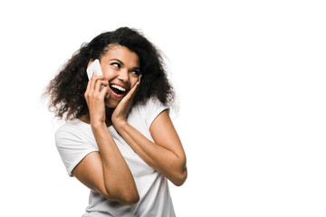 cheerful african american girl talking on smartphone isolated on white