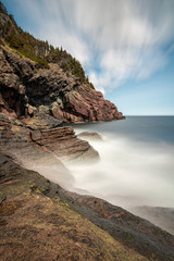 Dramatic seascape with silky smoothed out ethereal water meeting a rocky coast line. 