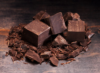 Closeup dark chocolate pieces on a wooden background