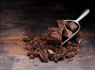 Dark chocolate on a wooden background and metal scoop