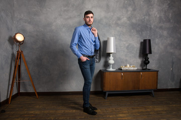 Handsome young man standing in interior on gray background