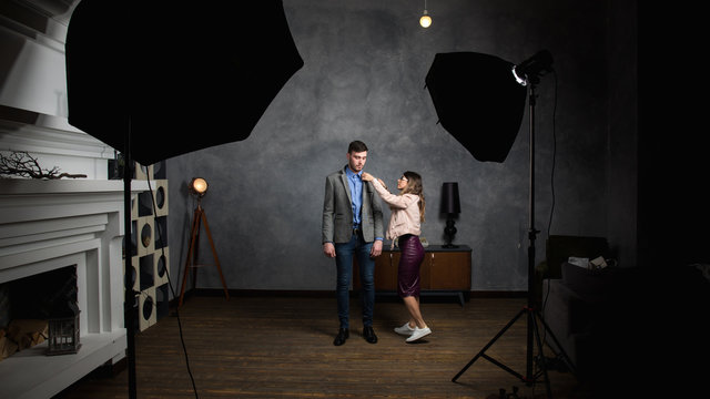 young beautiful woman helps to dress a man together in photo studio