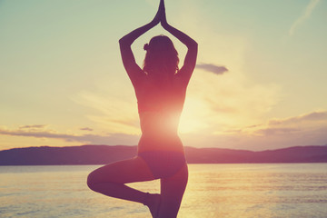 Young woman practicing yoga on the sandy beach.