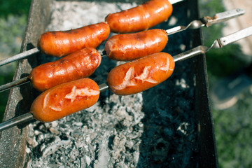 Juicy wieners on skewers over charcoal.Smoke and aroma around.