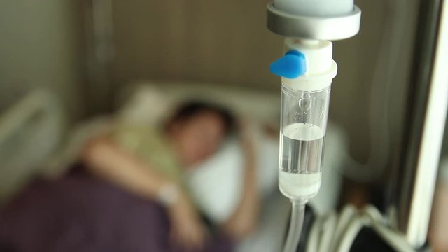 dripping of saline solution with blurred female patient sleep on the bed and covered with a blanket