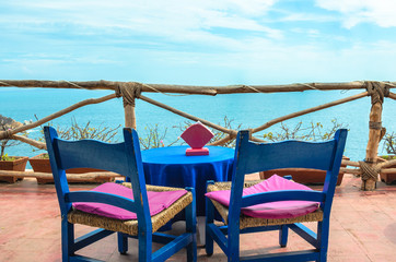 Coffee table on rustic balcony, with cliff and blue sea in Acapulco