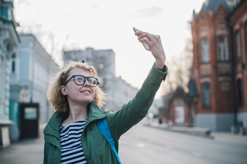 Young woman making selfie on the background of the European sunny street.