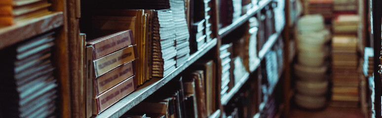 panoramic shot of retro books on wooden shelves in library - obrazy, fototapety, plakaty
