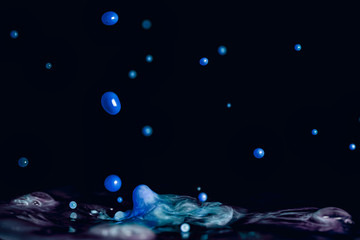 A colorful splash of vivid blue liquid isolated against a black background