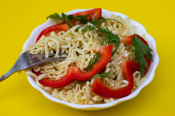 Instant noodles with red sweet peppers and greens in a white bowl. Appetizing Egg Noodles