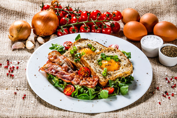 Breakfast - toasted bread with fried egg, bacon and vegetables