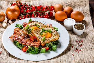 Breakfast - toasted bread with fried egg, bacon and vegetables