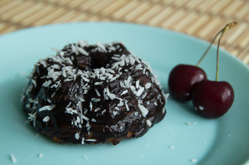 Chocolate cake with coconut, cherries and tea on a plate