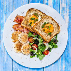 Breakfast - toasted bread with fried egg, bacon and vegetables