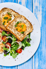 Breakfast - toasted bread with fried egg, bacon and vegetables
