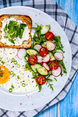Breakfast - fried egg, toasts and vegetable salad