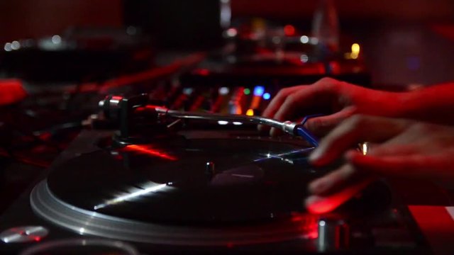  DJ working playing music with his equipment on festival. Professional DJ turntable records player, vinyls and sound mixer. Disc jockey mixing sounds, audio and songs in nightclub.DJ scratching a reco