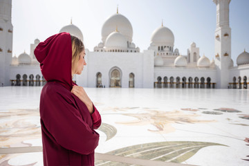 Woman at Abu Dhabi Mosque. Wearing a red Hijab looking at the Sheikh Zayed Grand Mosque in UAE....