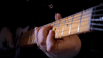 musician playing guitar at studio behind the glass with water drops