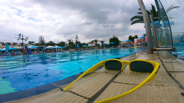 Sunglasses are lying on the pool edge covered with water