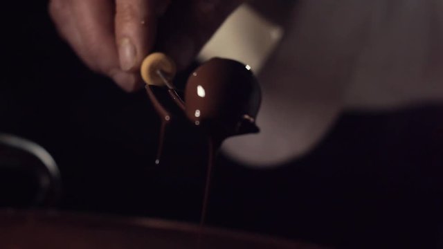 A chocolatier removes a hand made luxury treat from a bowl of melted chocolate