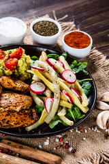 Grilled chicken fillet and vegetables on wooden table