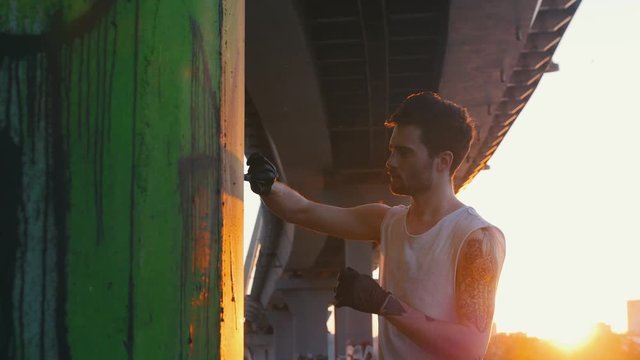 Man with marker pen drawing colorfull graffity under the bridge at the suny day