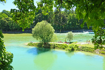 Fototapeta na wymiar Munich, summer view of Isar river with people sun bathing on the the Praterinsel island