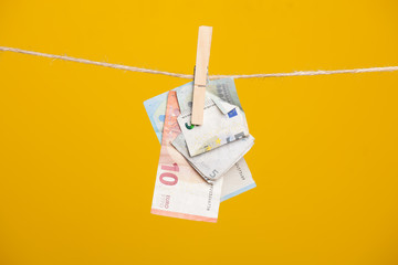 Billetes de Euro sobre fondo amarillo, colgados de una cuerda y sujetos por unas pinzas de madera...