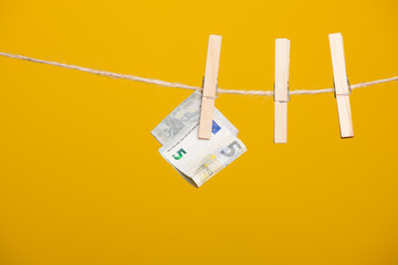 Billete de dinero en euros sobre una cuerda y sujeto por una pinza de madera de colgar la ropa.