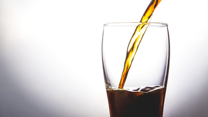 pouring cola into glass with ice on white background Copy space