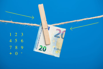 Billete de dinero en euros sobre una cuerda y sujeto por una pinza de madera de colgar la ropa.