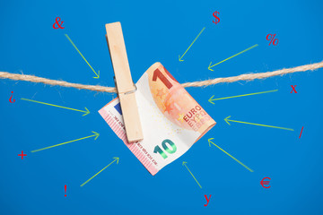 Billetes de Euro sobre fondo azul, colgados de una cuerda y sujetos por pinzas de extender la ropa. La banca lo utiliza como materia prima, las empresas para pagar a sus empleados.