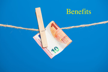 Billetes de Euro sobre fondo azul, colgados de una cuerda y sujetos por pinzas de extender la ropa....