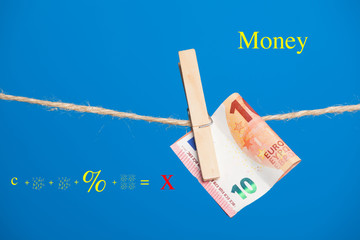 Billetes de Euro sobre fondo azul, colgados de una cuerda y sujetos por pinzas de extender la ropa....