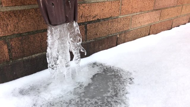 Frozen water drain spout on home after snow storm