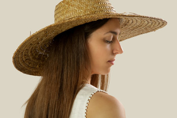 Studio portrait of a young brunette wearing wide brim straw hat 