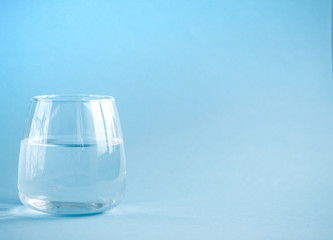 a glass of plain water on a blue background