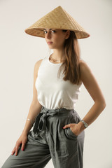 Studio portrait of a young brunette wearing traditional rice paddy straw hat 