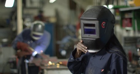 4K Portrait beautiful female welder smiling & giving flirty look to camera. Slow motion.