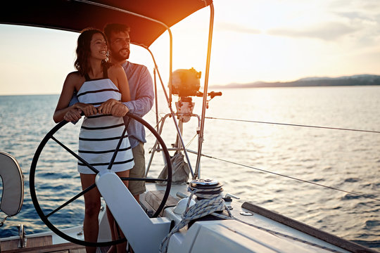 Romantic couple sailing on the luxury boat together and enjoy at sunset.